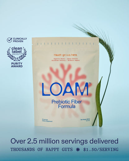 A stand-up pouch of LOAM Prebiotic Fiber Formula centered on a light blue gradient background, with a wheat stalk placed to the right and award badges on the left. Text at the bottom reads 'Over 2.5 million servings delivered' and 'THOUSANDS OF HAPPY GUTS'